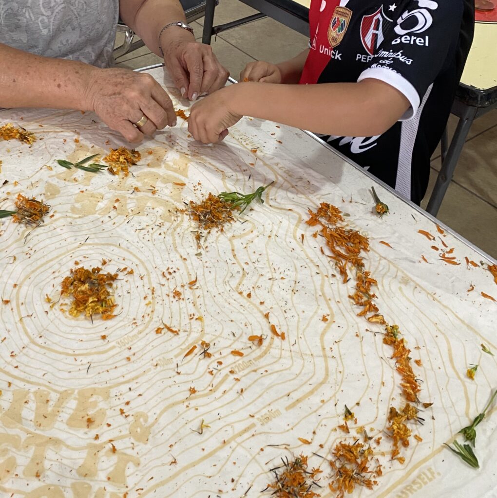 Kids eco-printing with marigold petals on cotton bandanas during a natural dye workshop.